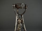 a silver vase on a stand with a bird on it