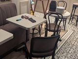tables and chairs in a restaurant with a bar in the background