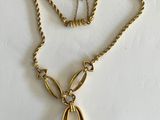 a close up of a gold necklace with a tear shaped pendant on it