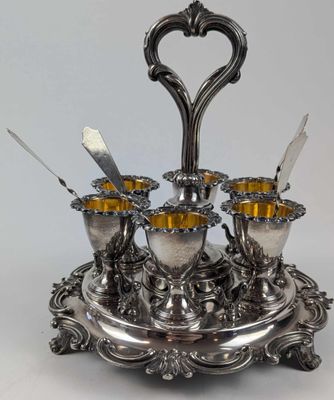 un plateau en argent sur lequel sont disposées quatre tasses et cuillères en argent
