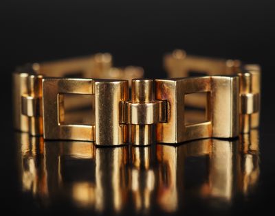 une image montrant un gros plan d'un bracelet en or posé sur une surface noire