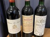 three bottles of wine are sitting on a table in front of a blue curtain