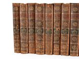 several old books are lined up in a row on a white surface