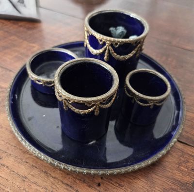 quatre tasses bleues posées sur une assiette bleue, sur une table en bois