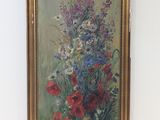 tableau représentant un bouquet de fleurs dans un cadre doré, accroché à un mur blanc