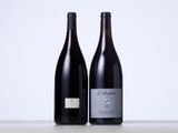 two bottles of red wine sitting next to each other on a table