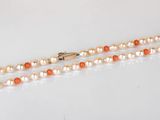 un collier de perles orange et blanches avec un fermoir en or