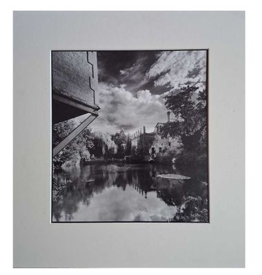 black and white photograph of a river with a bridge in the background