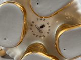 a white and gold vase that has five small flowers on it