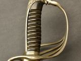 a close up of a sword with a gold handle on a gray surface