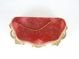 an old red and gold tray with a handle on a white surface