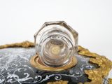 a glass bottle sitting on top of a black and gold plate