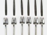 six forks are arranged in a row on a white surface