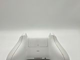 a close up of a white game controller on a white surface