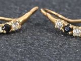 une paire de boucles d'oreilles dorées ornées de pierres noires et blanches