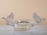 two birds sitting on top of a glass candle holder