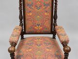an old chair with a colorful upholstered back and arms