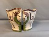two vases with faces painted on them on a table
