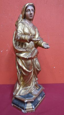 gold statue of a woman holding a cross on a red surface