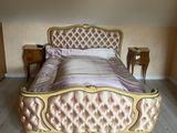 a bed that has a gold frame and a pink bed cover