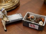 une figurine représentant une femme assise sur un lit, à côté d'une boîte contenant divers objets