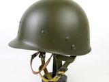 an army green helmet on a black stand against a white background