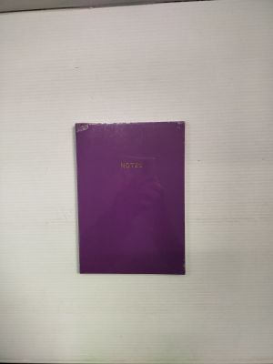 une photo d'un livre violet posé sur un mur blanc