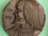 une image représentant une médaille de bronze sur laquelle figure le visage d'un homme