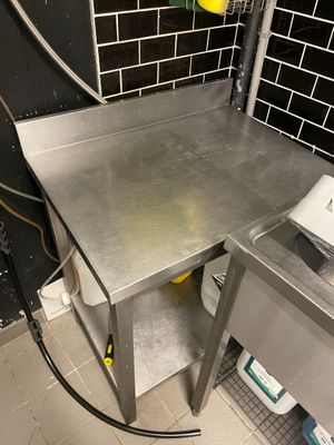 a stainless steel table in a kitchen with a hose attached to it