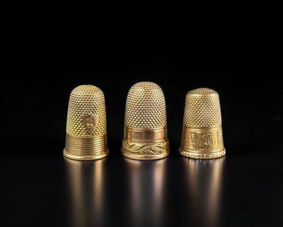 trois dés à coudre dorés sur un fond noir
