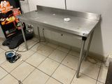 a stainless steel table in a kitchen with a sign on the wall