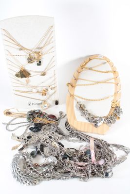 several necklaces and a mirror on a white surface with a white background