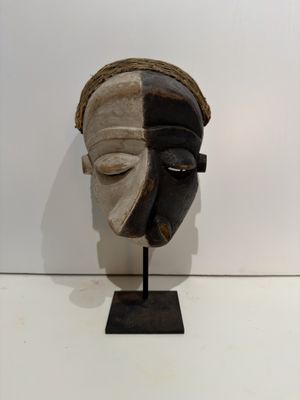 an image of a wooden mask on a stand on a white surface