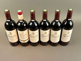 six bottles of wine are lined up in a row on a table