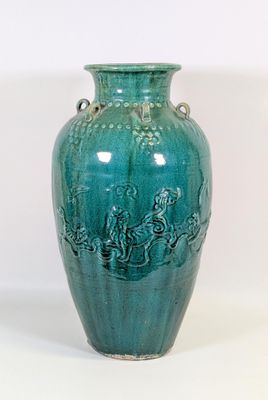 un vase vert muni d'une anse sur fond blanc