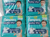 quatre paquets de couches Pampers Baby Dry empilés les uns sur les autres