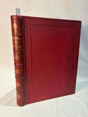 an old book with a red cover sitting on top of a white table