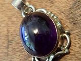 a close up of a purple stone pendant on a wooden surface
