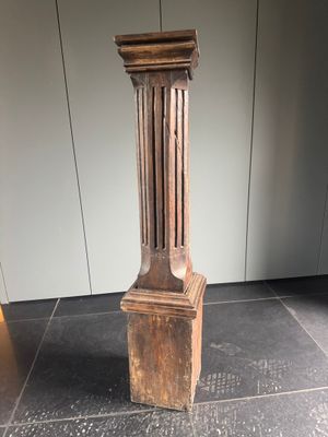 une grande colonne en bois posée à même le sol dans une pièce