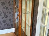 a glass display cabinet in the corner of a room