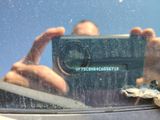 reflection of a man taking a picture of himself in the rear window of a car