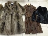 three coats of fur lined up on a tile floor in a store