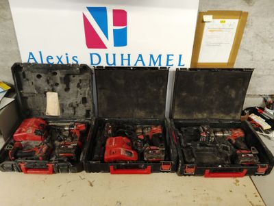 trois outils rouges et noirs dans un coffret posé sur une table