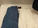 two pairs of pants and a jacket laying on a bed
