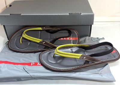 une paire de tongs pour homme dans une boîte, accompagnée d'une paire de lunettes de soleil