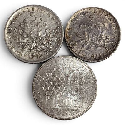 three different types of silver coins on a white surface