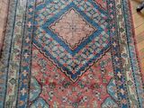 un tapis oriental posé sur un parquet, avec une chaise en arrière-plan