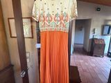 une robe plissée orange suspendue à un cintre dans une pièce