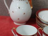 five cups and a pitcher sitting on a red table