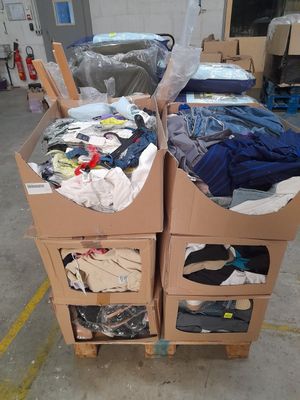deux cartons sur lesquels sont posés des vêtements, dans un entrepôt